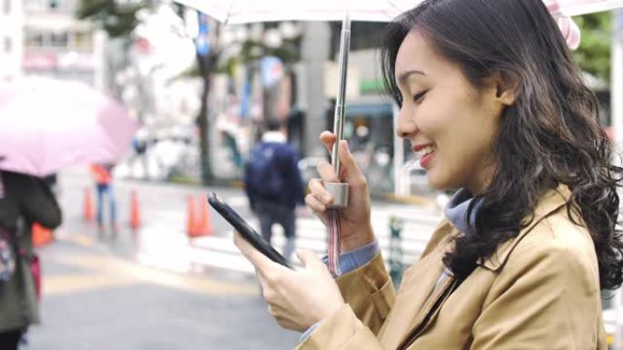 亚洲妇女在雨中使用智能手机发短信