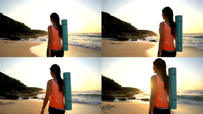 瘦弱的女人拿着瑜伽垫走在海滩上的后景