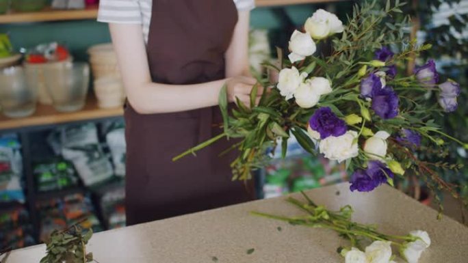 年轻的花店在商店里拿着一束美丽的鲜花，摆放花束