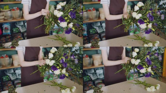 年轻的花店在商店里拿着一束美丽的鲜花，摆放花束
