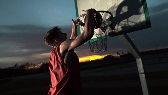 MS超级慢动作年轻人在黄昏时在篮球架上扣篮