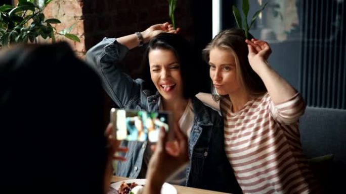女性朋友使用智能手机在咖啡馆与鬼脸合影留念