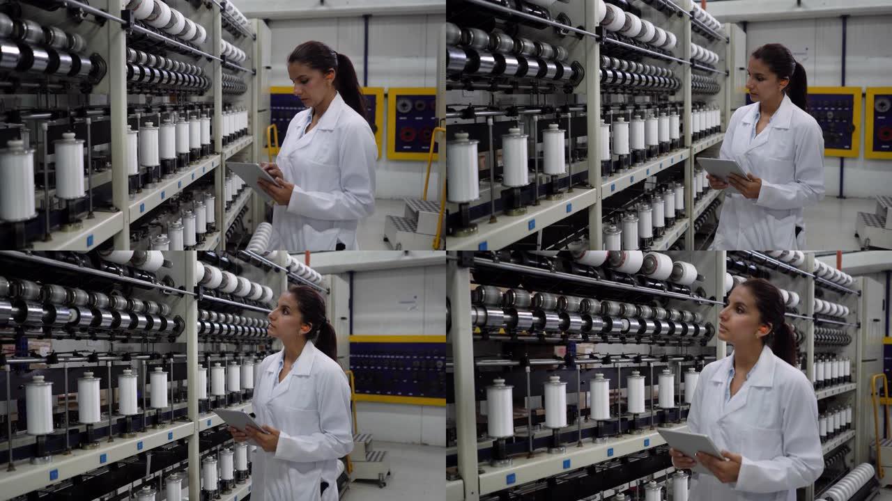 在胶带工厂工作的妇女在生产线上检查并拿着平板电脑时戴着护耳器