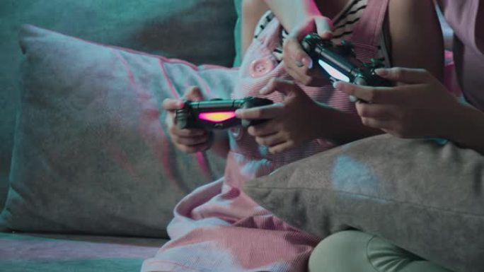 关闭兄弟姐妹女孩一起玩视频游戏的4k分辨率手，并为他们在家里的客厅获胜感到高兴。两个姐姐喜欢在冠状病