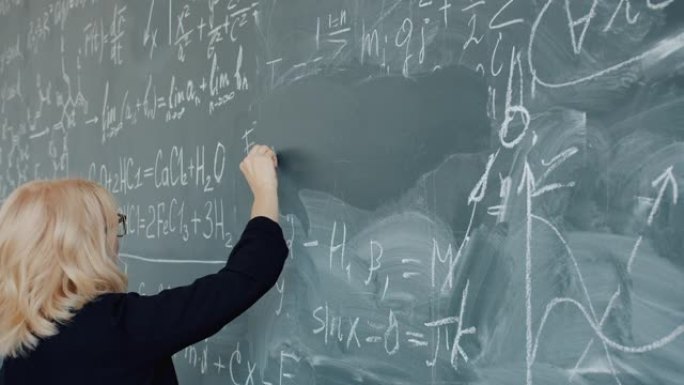 女化学老师的慢动作严肃的女人在黑板上写公式