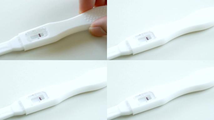 女性手把怀孕测试器放在白色桌子上。