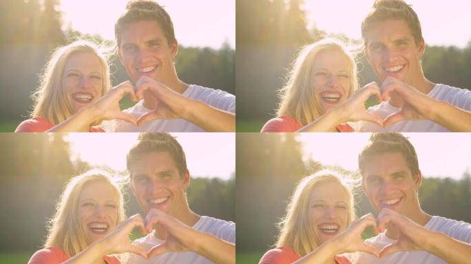 镜头耀斑: 年轻女子在与男友做心形时大笑。