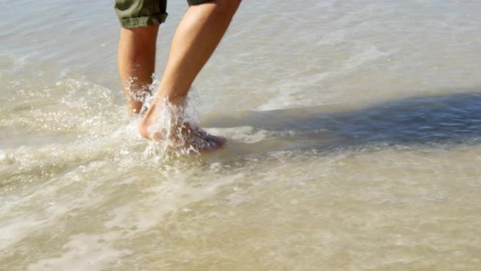男子在阳光明媚的日子在海滩上水上行走4k