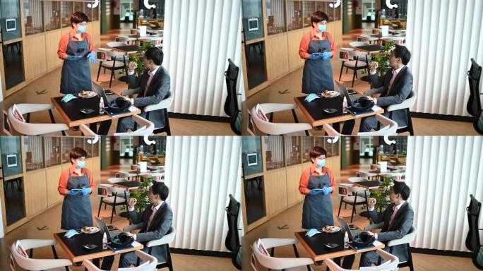 一位亚洲华人小咖啡馆的女店主正在和她的顾客聊天，让她在咖啡馆里点餐，这是新的正常的社交距离标准操作程