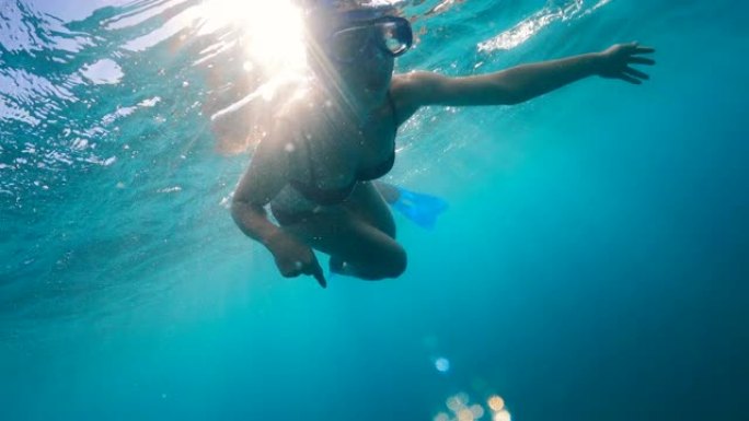 一个戴着面具和鳍的女人正在水下潜水