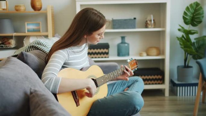 迷人女孩的慢动作享受音乐独自在公寓里弹吉他