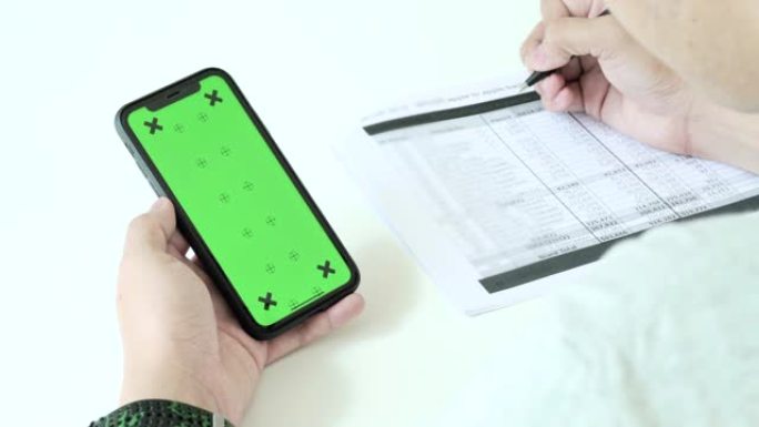 男人在家中使用，滚动和查看带有色度键的智能手机绿屏。检查工作