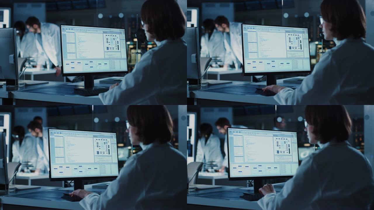 肩膀上的镜头: 女IT科学家使用计算机显示系统监视和控制程序。在背景技术开发实验室中，科学家、工程师