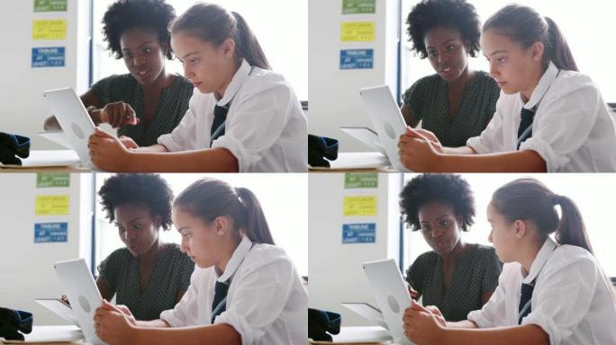 带数字平板电脑的女高中导师给女学生在办公桌上穿制服一对一的学费