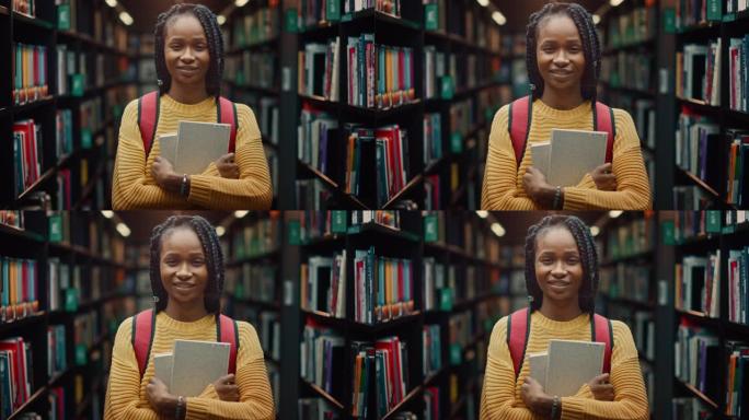 大学图书馆学习: 一个聪明美丽的黑人女孩的肖像，拿着学习教科书微笑着看着相机。真实的学生为课堂作业、