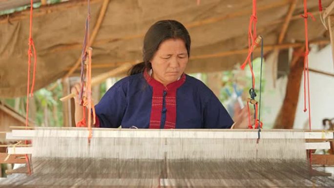 工艺村的传统纺织品制造，老妇女在木制织机上工作，纺纱制造丝绸或棉织物。泰国的丝织。
