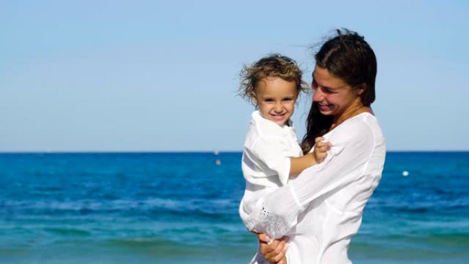 母女一家人快乐地在海上玩耍，穿着白衣服拥抱微笑，背景为海水蓝色。