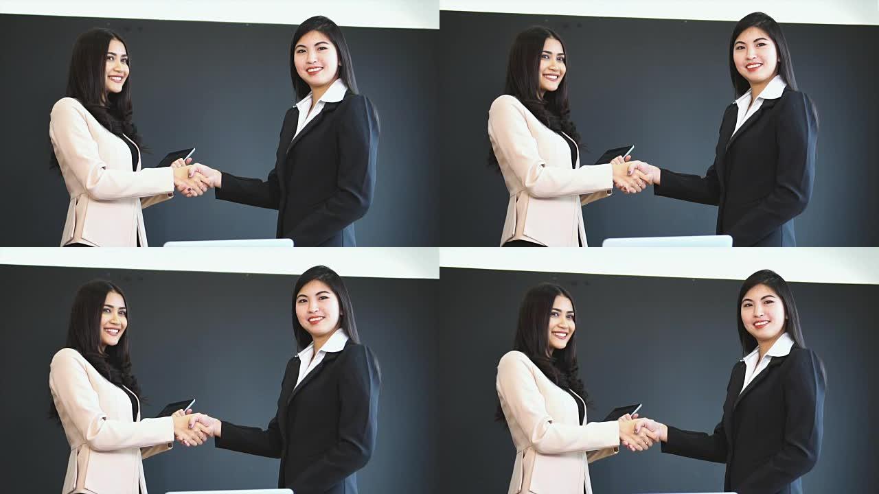 两名亚洲女商人握手的4k慢动作镜头，为成功工作计划项目在办公室，业务和会议成功概念