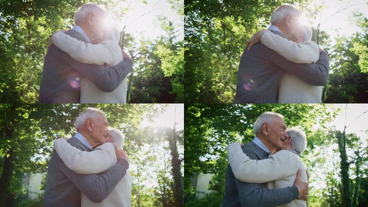 在阳光明媚的日子里，在绿色公园里，一对老年夫妇的慢动作拥抱着深情，以示他们永远的爱和尊重