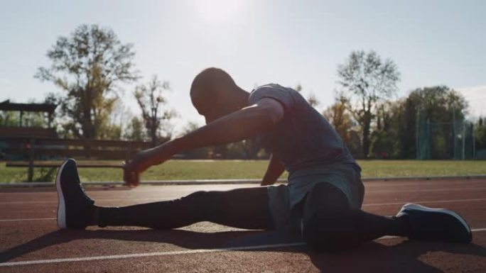 年轻的非洲男运动员的慢动作特写镜头正在为在阳光下开始田径比赛而热身。