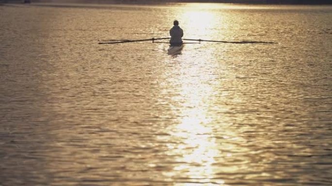 日落时男子在河里划桨划艇