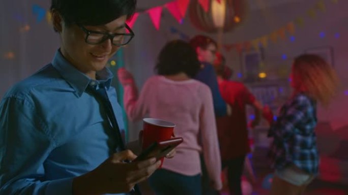 在野外聚会上: 快乐的亚洲男人使用智能手机，而不是与其他人跳舞。