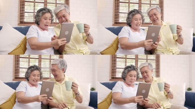 亚洲老年夫妇在家使用平板电脑和在客厅喝咖啡，夫妇在家放松时躺在沙发上享受爱情时刻。享受时间生活方式老