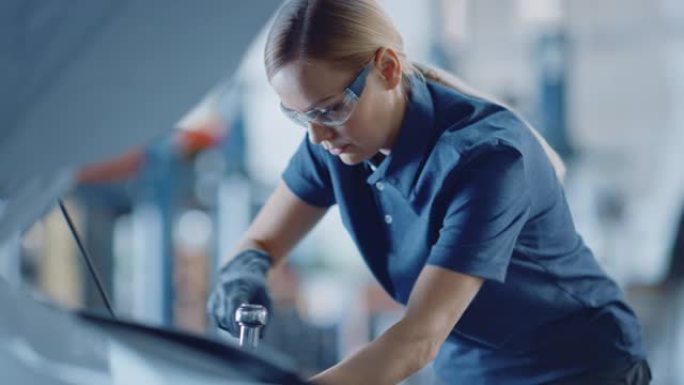 一名女机械师在汽车服务中工作的慢动作肖像镜头。授权女人修理引擎。她在用棘轮。现代清洁车间。