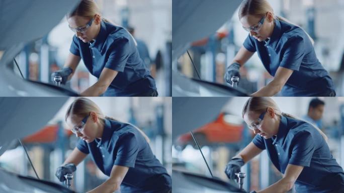 一名女机械师在汽车服务中工作的慢动作肖像镜头。授权女人修理引擎。她在用棘轮。现代清洁车间。