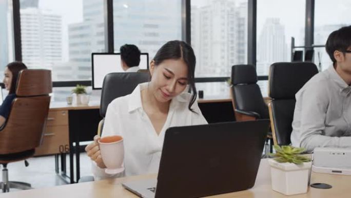4K UHD: 亚洲员工，女性在现代办公室背景的笔记本电脑上工作。