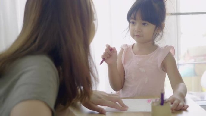 在母亲的帮助下，可爱可爱的亚洲女孩在家做作业。