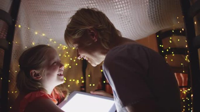 白人妇女和女儿在家中使用数字平板电脑的侧视图
