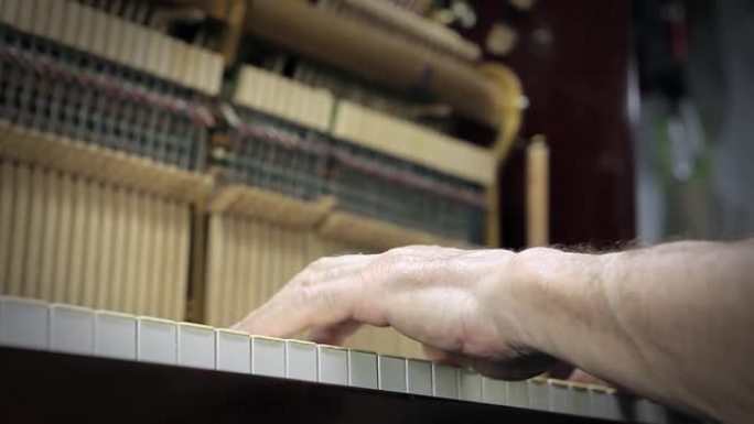 男性手在弹一架旧钢琴。特写。
