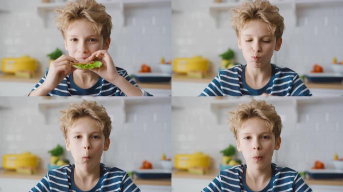可爱的小男孩在厨房餐桌上吃三明治的肖像。帅哥吃一口健康零食。特写慢动作肖像