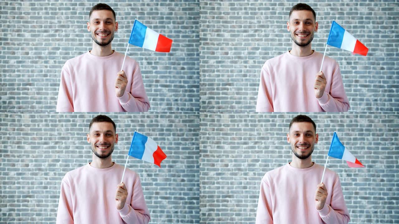 砖墙背景上带有法国国旗的快乐年轻人肖像