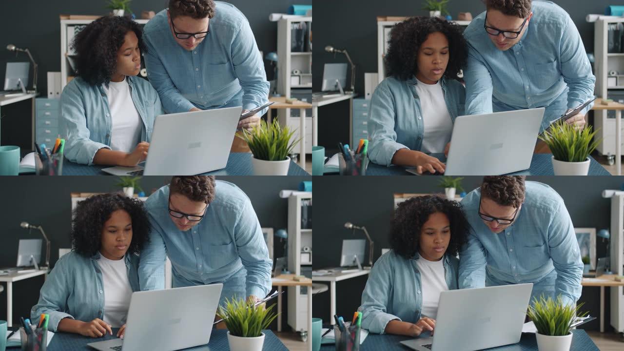 男女上班族在室内办公室内使用笔记本电脑聊天