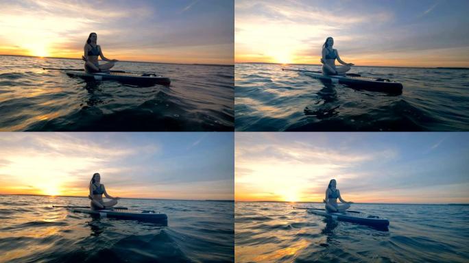 一个女人在海里的桨板上休息，冥想。4K。