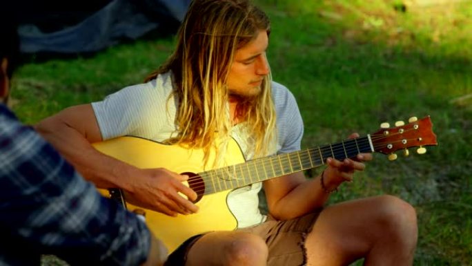 男子在森林营地弹吉他4k