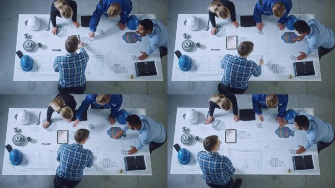 工业工程师团队依靠办公桌，分析机械蓝图，解决建筑问题，在平板电脑上咨询项目，检查金属部件。平放俯视图