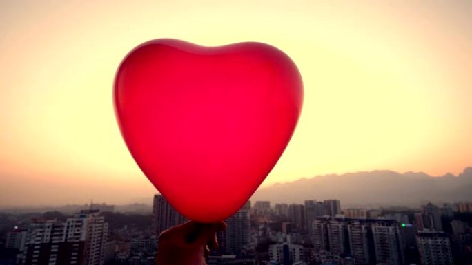 手持红色气球城市背景爱心气球温馨