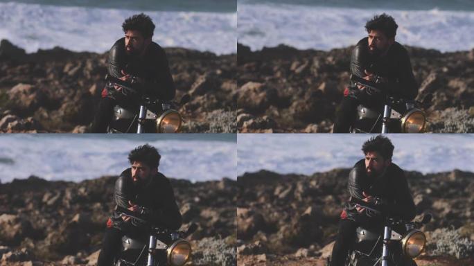 英俊的男人靠在海边的经典摩托车上