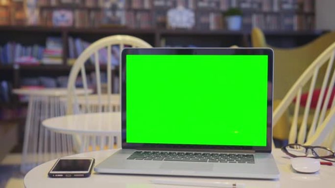 在图书馆中倾斜带有绿色屏幕的计算机笔记本电脑，没有人