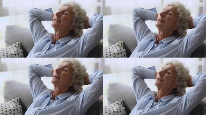 快乐放松的老妇人闭着眼睛躺在沙发上休息