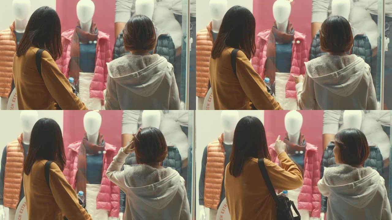 两名年轻的亚洲妇女看着商店的橱窗，慢动作