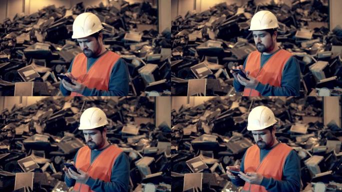 垃圾，塑料回收厂。戴着安全帽的垃圾填埋场工人正在操作智能手机