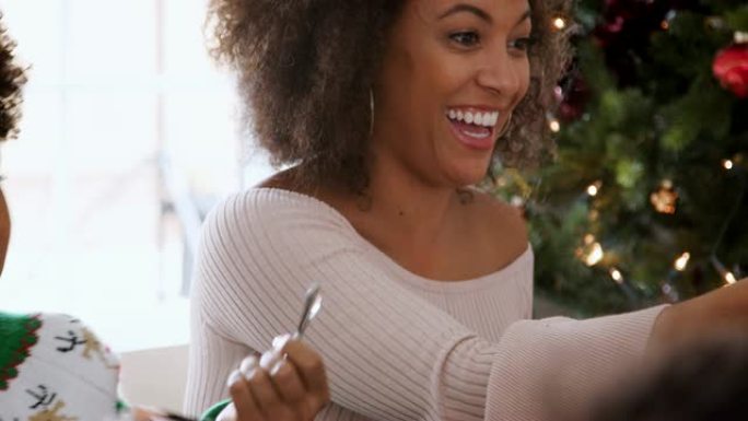 年轻的黑人妇女坐在圣诞晚宴上，和她的多代家庭一起拉饼干，特写