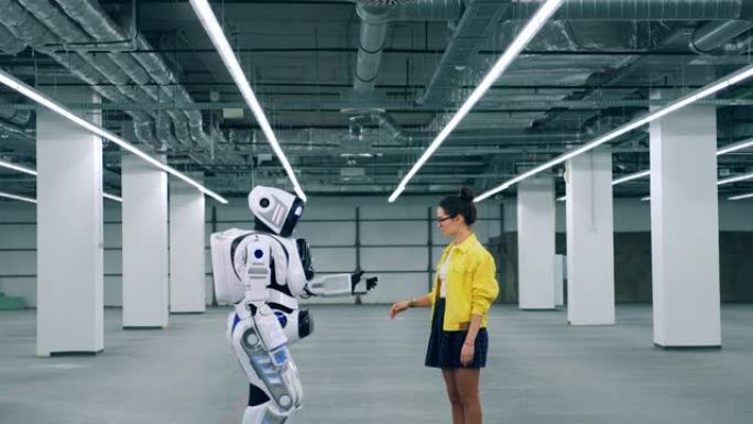 女孩和机器人在房间里见面时摸手。