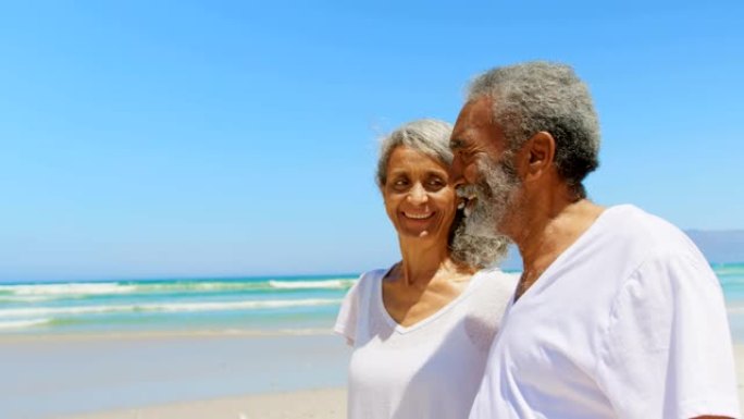 快乐活跃的老年非洲裔美国夫妇在阳光下4k在海滩上散步的侧视图