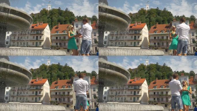 慢动作: 一对夫妇在阳光明媚的日子里牵着手在喷泉旁旋转。