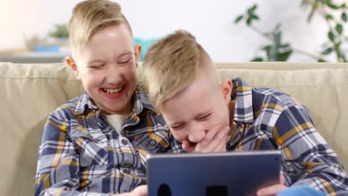 高加索双胞胎兄弟在平板电脑上观看有趣的视频